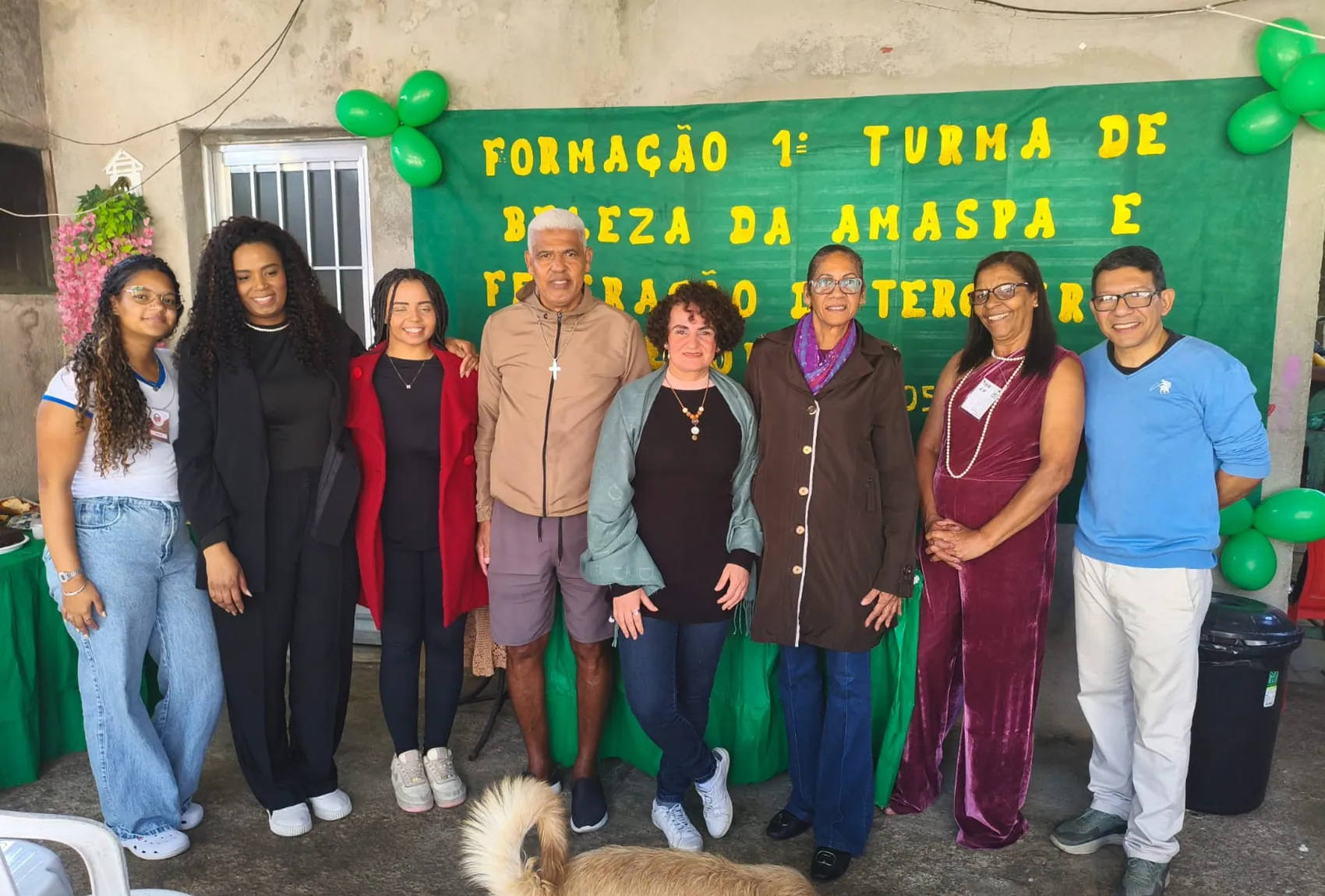 Primeira turma do Projeto Beleza reunida diante da faixa de formatura
